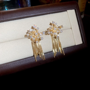 Macro view of golden firework tassel earrings with pearls and crystals on velvet