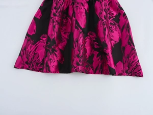 Detail of elegant black jacquard fabric with vibrant rose red floral pattern on dress hem