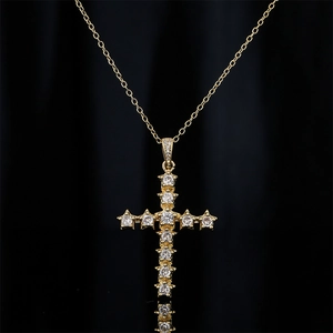 Macro de pendentif croix dorée avec zircons sur fond de tissu en soie noire