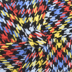 Macro shot of colorful houndstooth fabric texture and top button on a baseball cap