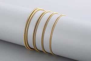 Detail of four golden stainless steel snake chains in various thicknesses on a display