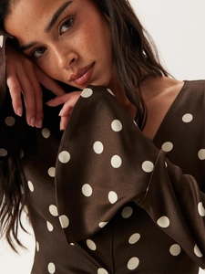 Détail de la robe marron à pois avec décolleté en V et manches longues drapées