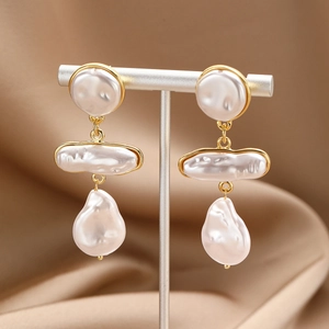 Detailed macro view of baroque pearl earrings with golden edges on silk background