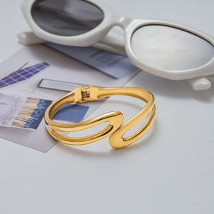 Macro detail of 18K gold plated stainless steel layered bangle with artistic curved lines
