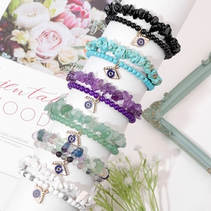 Detailed shot of multi-layered natural stone bracelets with evil eye charms on stands