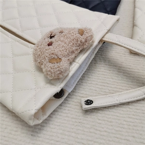 Close-up of white quilted leather car tissue holder featuring a cute brown plush bear