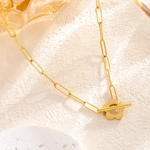 Golden paperclip chain necklace with floral toggle clasp on minimalist background