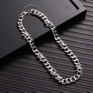 Detail of silver thorn Cuban link necklace with barbed wire knots on a dark background