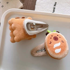 Detail of plush cartoon hamburger and paw hair clips on a tray for autumn fashion