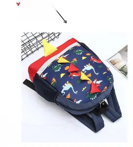 Detail view of the colorful dinosaur print and 3D felt spine on a navy kids' backpack