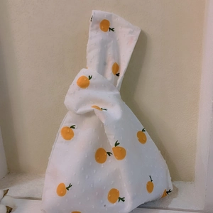 Japanese knot wrist bag with orange pattern and 3D polka dots on white cotton fabric