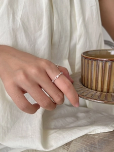 Detailed view of a slender 925 sterling silver twisted knot ring on a finger