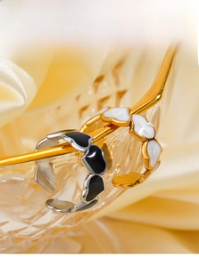 Detail of adjustable black and white enamel heart rings on a decorative glass edge