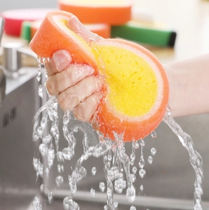 Action shot of squeezing high-elasticity orange sponge with flowing water in kitchen sink