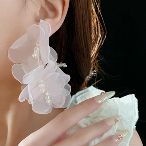 Gros plan d'un mannequin portant des boucles d'oreilles fleurs en maille rose et perles