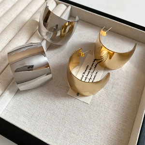 Macro view of wide C-shape earrings in gold and silver finish on a jewelry box