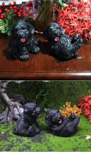 Detalle de dos figuras de cachorro Labrador negro en poses sentada y rodante con pelaje