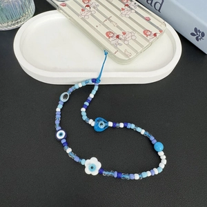 Detail view of Bohemian evil eye beaded phone strap with blue and white beads and flower