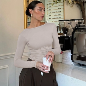 Dettaglio della maglia beige a maniche lunghe con taglio aderente e scollo rotondo fine