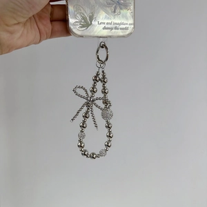 Detail of silver beaded phone strap with rhinestone bow on transparent butterfly case