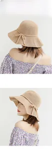 Detail of wide brim straw sun hat with bow tie decoration and breathable knit texture
