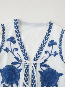 Close-up of white vest top featuring intricate blue floral and geometric embroidery details