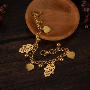 Detailed close-up of golden stainless steel Hamsa hand and heart charms on a link chain