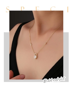 Close-up of golden heart lock necklace with zircon stones worn by a model