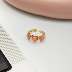 Détail de trois cœurs en œil de chat rose sur une bague ajustable en acier doré