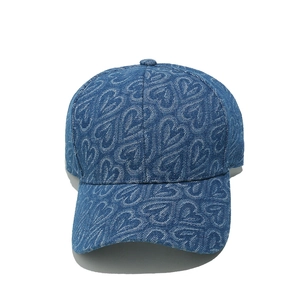 Close-up of heart pattern texture on dark blue denim baseball cap for women