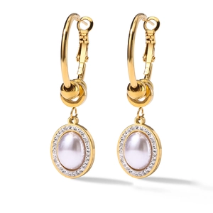 Macro shot of gold hoop earrings with pearl and zircon inlay on a white background