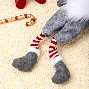 Close-up of Christmas gnome detail with striped socks, grey pants and candy cane prop