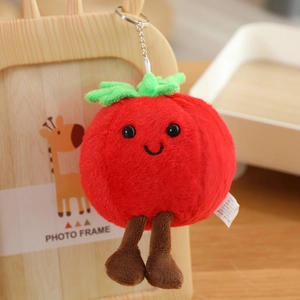 Cute plush tomato keychain with smiley face and green leaves hanging on a frame