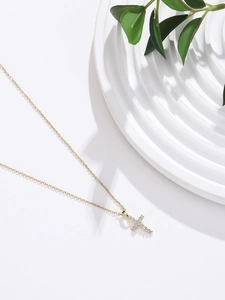 Macro shot of gold cross pendant with sparkling zircon inlays on delicate chain