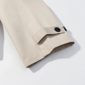 Gros plan détaillé des poignets du trench-coat beige avec boutons noirs et coutures