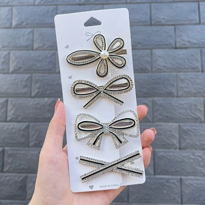 Close-up of four-piece hair clip set with pearls and rhinestones on white card