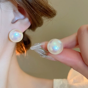 Macro detail of large iridescent pearl stud earrings with metallic aurora gloss finish