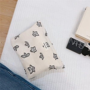 Close-up of a minimalist canvas cosmetic bag featuring black butterfly prints and text label