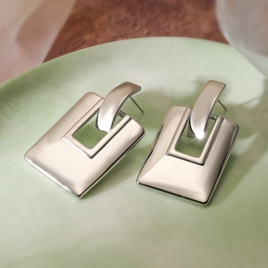 Detailed view of silver-plated geometric earrings on a green ceramic display tray