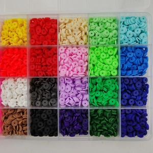 Flat lay of 20 vibrant colors of clay heishi beads neatly organized in a clear plastic box
