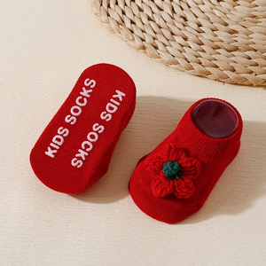 Detail of red baby socks with knit flowers and anti-slip rubber grips on the soles