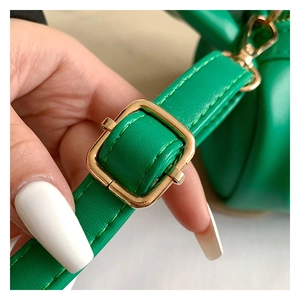 Detail of green leather strap with adjustable gold metal buckle on a shoulder bag