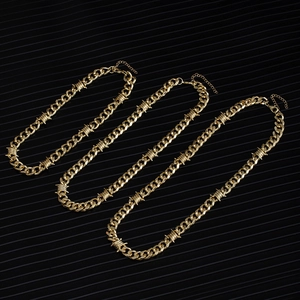 Three gold punk-style Cuban necklaces with thorn knots on a dark textured surface