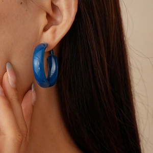 Vue détaillée de boucles d'oreilles créoles bleu Klein épaisses portées par un modèle