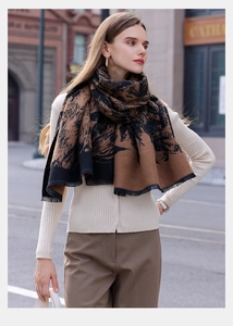 Close-up of soft cashmere-like scarf featuring brown abstract patterns and fringe edges