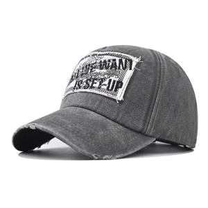 Détail d'une casquette vintage grise en coton lavé avec bord usé et écusson brodé