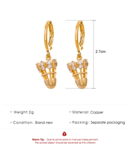 Détail des boucles d'oreilles volant en cuivre doré avec des zircons blancs sertis