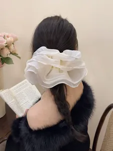 Detail of oversized white pleated mesh hair scrunchie styled in an elegant ponytail