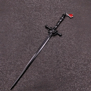 Detail of a black sword-shaped hairpin featuring a red heart pendant on a dark textured surface