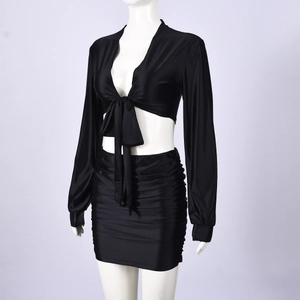 Detail view of black long sleeve tie-up crop top and ruched mini skirt set in glossy fabric
